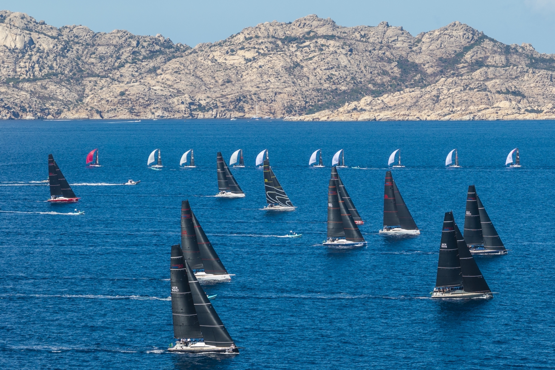 The ClubSwan 50 and ClubSwan 28 fleets racing with the island of Caprera in the background, Rolex Swan Cup 2026. Photo credit: Rolex/Studio Borlenghi